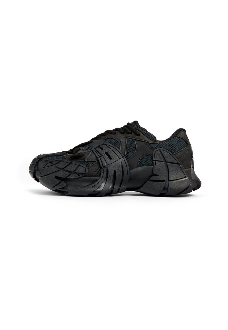 Scarpe sportive nere con tomaia in rete, suola in gomma testurizzata, design modellato unico e sistema di allacciatura integrato per una vestibilità sicura.