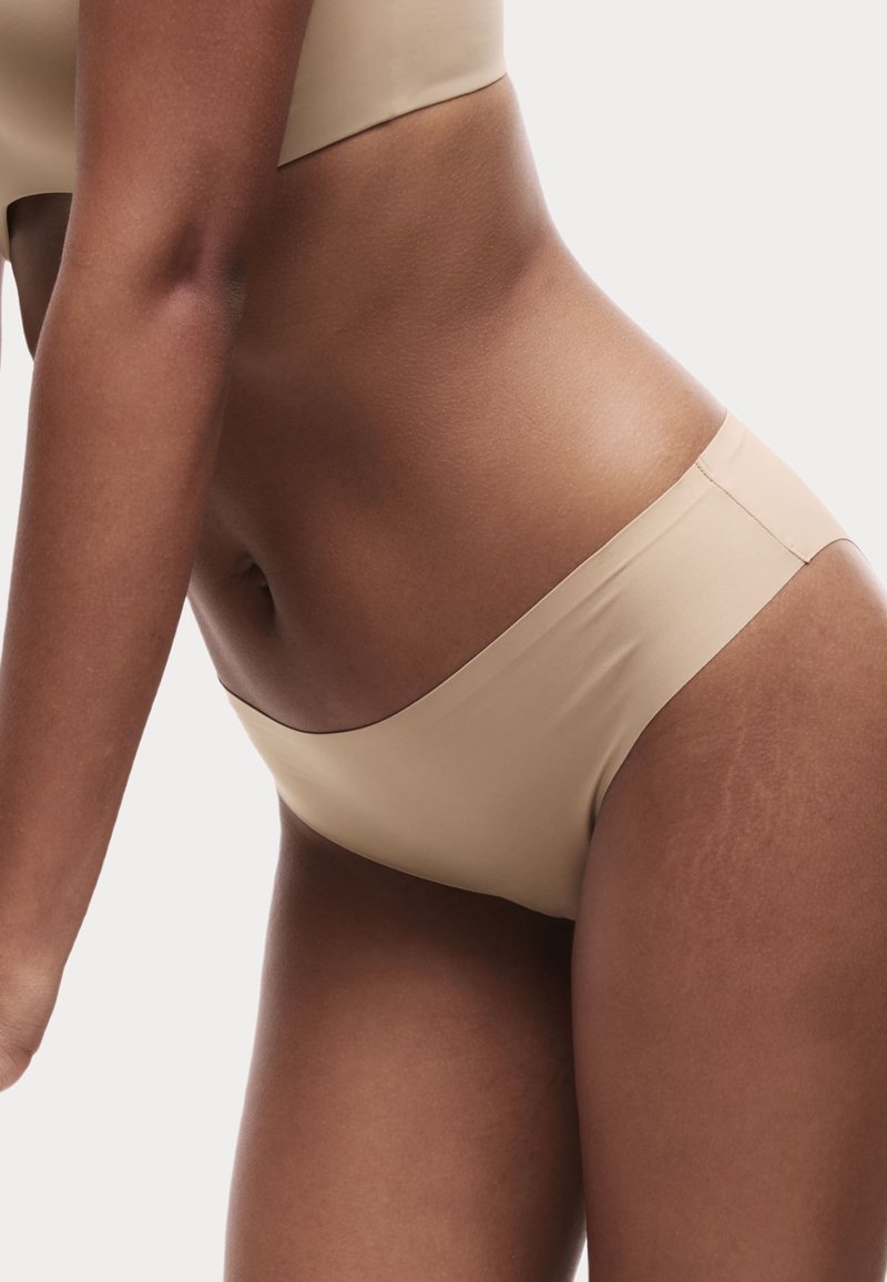 Beige seamlessly bikini nederdel med lav talje, glat tekstur og minimalistisk design, uden synlig hardware eller detaljer.