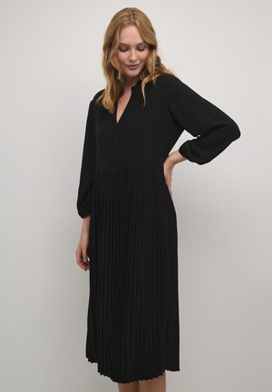 Black pleated dress with a v-neckline and balloon sleeves. Made from soft fabric, featuring a fitted bodice and flowing skirt.