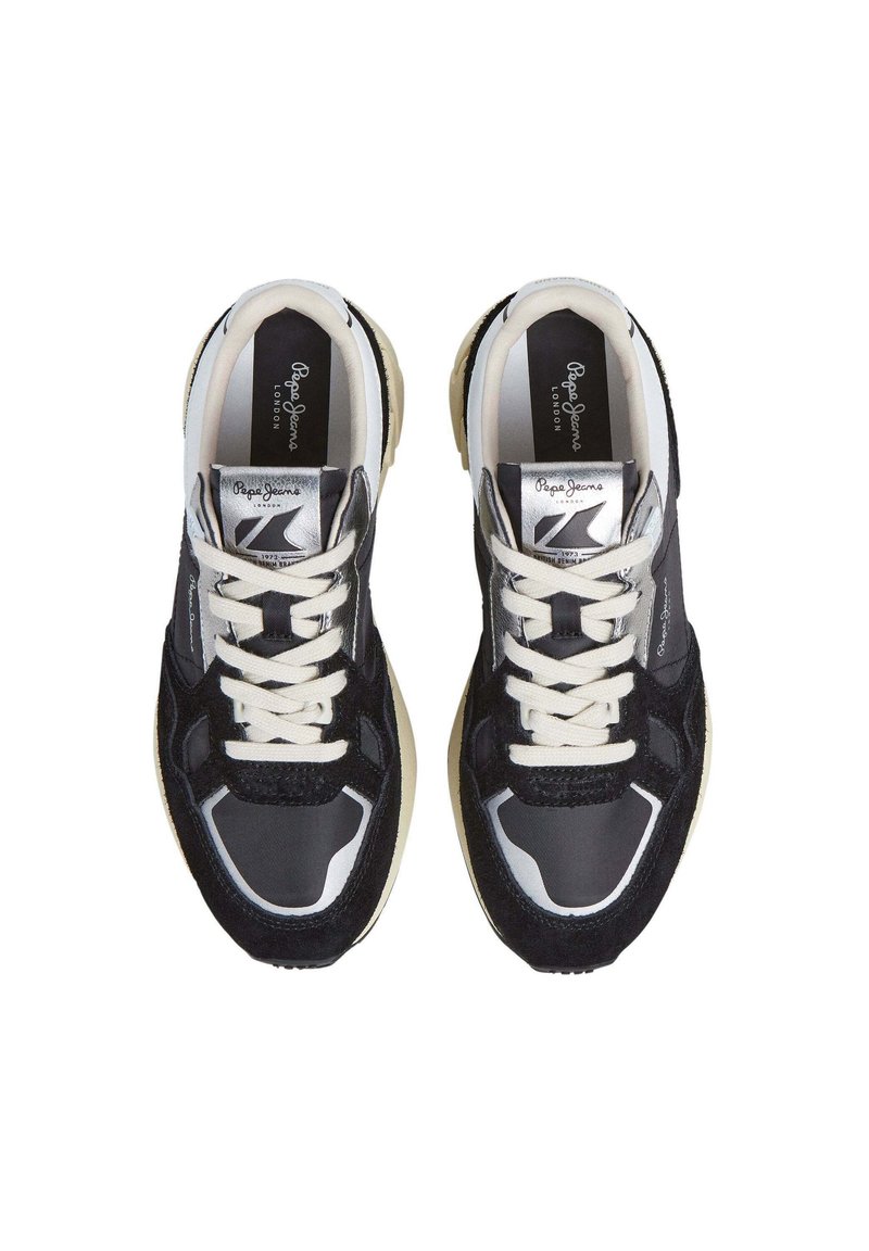 Zapatillas deportivas en negro y gris, con una mezcla de tela texturizada y material sintético liso, que presentan cordones blancos y una suela beige. Se aprecian detalles en plata.