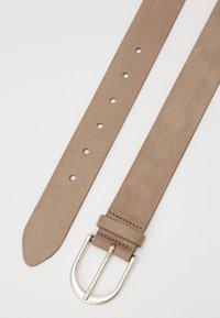 Ceinture en suédine beige avec boucle en métal argenté, dotée de plusieurs trous pour l'ajustement. Texture plate et lisse avec une extrémité effilée.