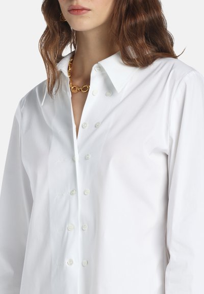 White button-up shirt with a classic collar, featuring a smooth texture, visible button placket, and subtle stitching details.