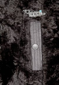 Tela de piel sintética negra y texturizada con un panel liso gris que presenta un botón metálico y un logo bordado que dice "Khuyо Roughfine".