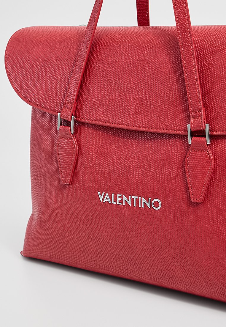 Rote, strukturierte Handtasche mit Klappenverschluss, doppelten Griffen, silbernem Zubehör und eingeprägtem "VALENTINO"-Logo auf der Vorderseite.