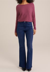 Burgundy ribbed pitkähihaine paita yhdistettynä korkeavyötäröisiin tummansinisiin leveälahkeisiin farkkuihin. Ominaisuuksiin kuuluu klassinen viiden taskun muotoilu ja vartalonmyötäinen siluetti.