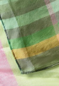 Geweven textiel met een ruitpatroon in tinten groen, geel en roze. Zachte textuur met een licht glanzende afwerking en onafgewerkte randen.