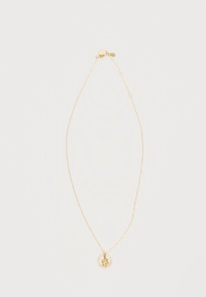 Delikatny złoty łańcuszek z okrągłą zawieszką, wewnątrz której znajduje się mała zawieszka w kształcie misia, na białym tle.