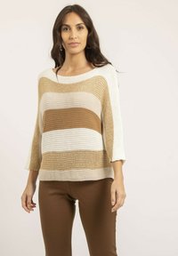 Pull en tricot avec des rayures horizontales crème, beige clair et beige foncé. Encolure bateau large, manches 3/4 et coupe décontractée. Assorti avec un pantalon marron.
