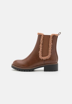 Bottines en cuir marron avec une semelle en caoutchouc, accent texturé et flou le long du col, et panneaux latéraux élastiques pour un enfilage facile.