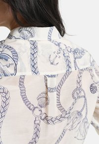 Leichtes, cremefarbenes Hemd mit einem blauen maritimen Muster aus Seilen, Muscheln und einem Anker. Taillierter Kragen und schlankes Design.