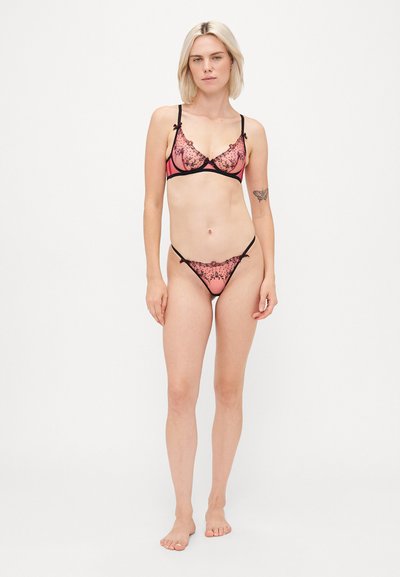 Różowy zestaw bielizny z koronkowymi wykończeniami i czarnymi akcentami; stanik w stylu bralette i stringi; przezroczysty materiał z kwiatowym wzorem; regulowane ramiączka.