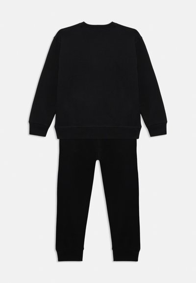 Schwarzes Baumwoll-T-Shirt und passende Hose. Das T-Shirt hat einen Rundhalsausschnitt und lange Ärmel; die Hose hat einen elastischen Bund und schmal zulaufende Bündchen.