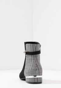 Černé semišové kotníkové boty s kostkovaným textilním zadním dílem. Disponují stříbrným akcentem a středně vysokým podpatkem. Celkový design je elegantní a strukturovaný.