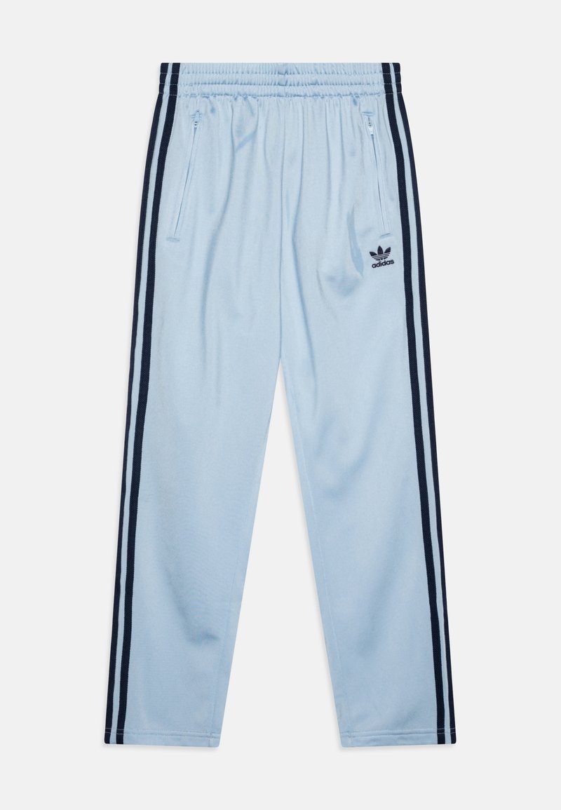 Pantaloni della tuta azzurri con una texture morbida, strisce laterali nere e tasche con cerniera. Presentano un piccolo logo Adidas nero sul retro.