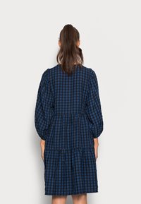 Blau- und schwarzkarierter Kleid mit Puffärmeln, einem mehrlagigen Rock und einem runden Ausschnitt, aus leichtem Stoff gefertigt.