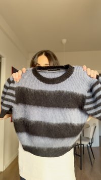 Suéter de punto suave con rayas horizontales negras y azules, cuello redondo, mangas cortas y un ajuste ligeramente oversize.