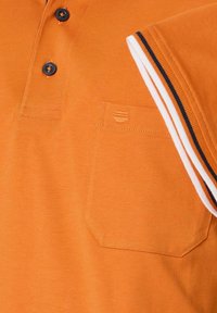 Pomarańczowa koszulka polo z kołnierzykiem na guziki, naszywaną kieszenią i pasami na rękawach w kolorze białym i granatowym. Wykonana z miękkiej bawełny.