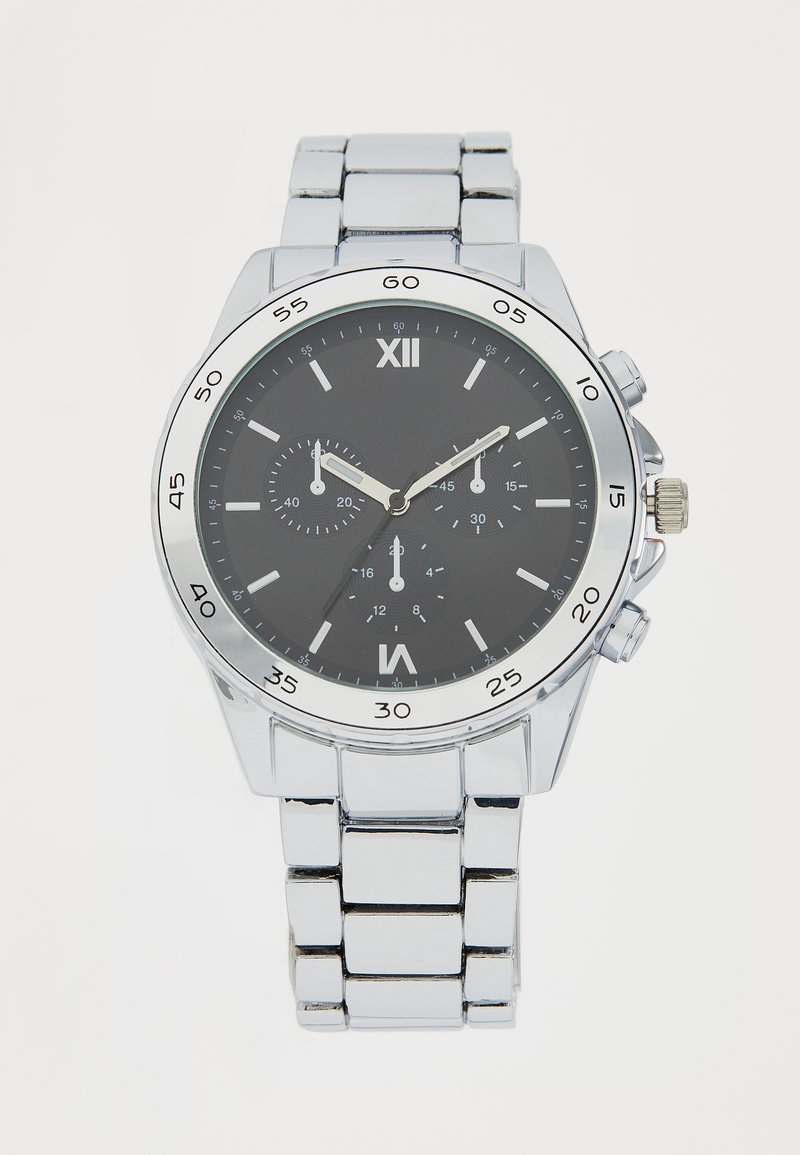 Montre-bracelet en métal argenté avec un cadran noir, des index horaires blancs et des sous-cadrans chronographiques. Elle est dotée d'un bracelet à maillons en acier inoxydable.