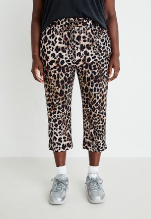 Leopardprint cropped broeken met trekkoord in de taille, gedragen met witte sokken en grijze sneakers bij een staand persoon.