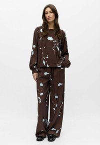 Ensemble de vêtements d'intérieur marron à motifs floraux comprenant un haut à manches longues et un pantalon à jambes larges, avec des motifs floraux bleu clair et une finition de tissu texturée.