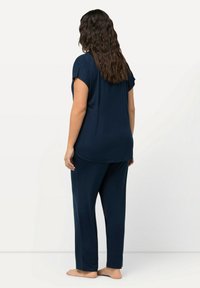 Mörkblå loungemiljö set i mjukt tyg, som har en avslappnad topp med korta ärmar och matchande raka byxor.