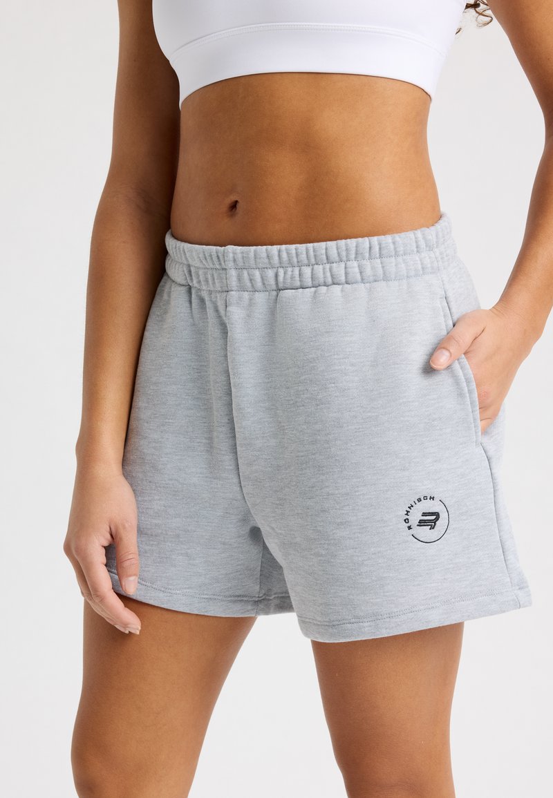 Pantalones cortos de mezcla de algodón gris con una cinturilla elástica, bolsillos laterales y un logo negro en el dobladillo inferior. Textura suave y ajuste relajado.