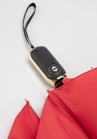 Red umbrella with a rounded black handle featuring a gold accent and a button, showing a portion of the canopy and metal tips.