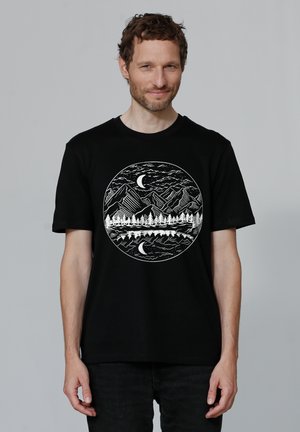 Black cotton t-shirt featuring a circular white graphic of mountains, trees, and moons, with a textured appearance and contrasting colors.