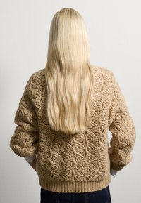 Gebreide beige trui met een textuurpatroon, geribbelde manchetten en zoom. Oversized silhouet met brede mouwen en een losse pasvorm.