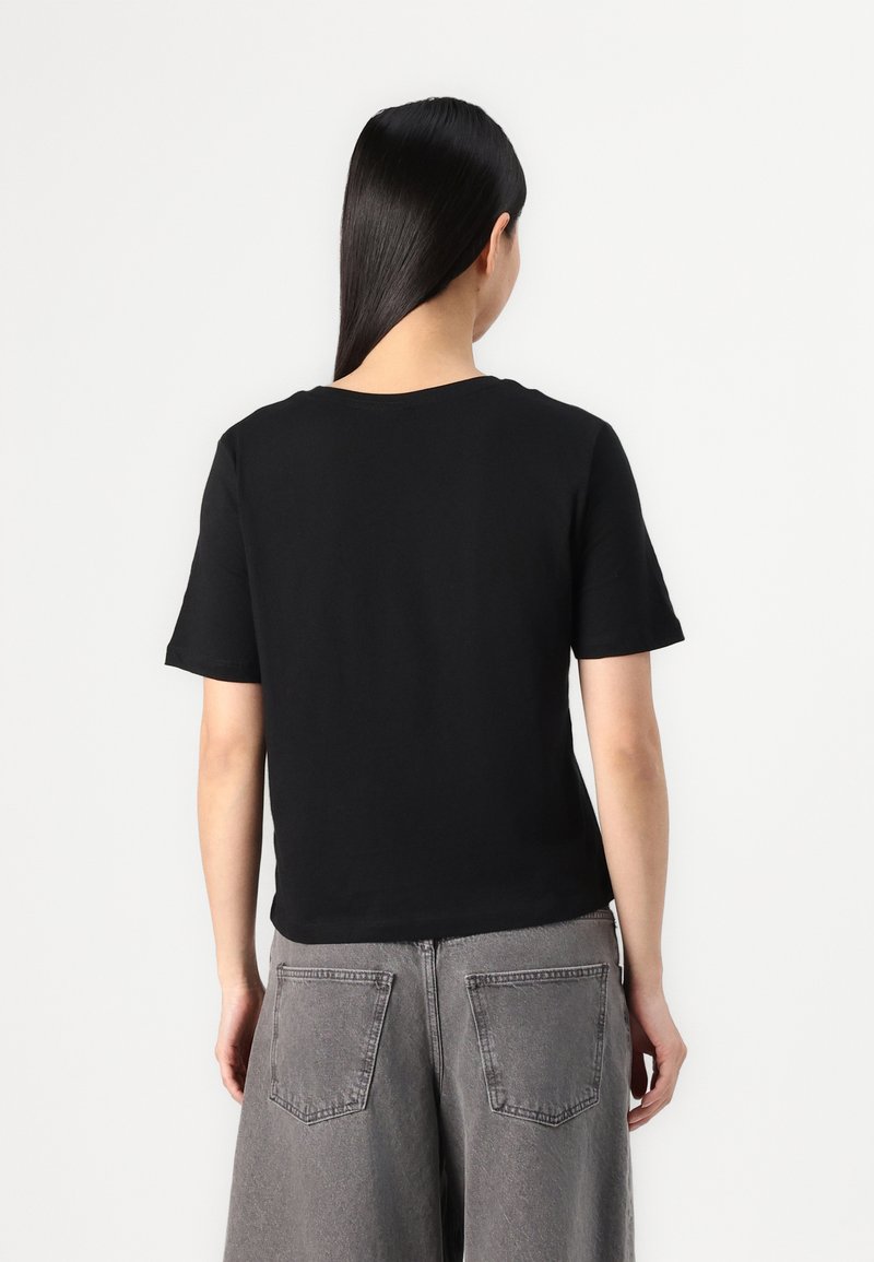 T-shirt noir à manches courtes avec un col rond, en tissu doux, associé à un jean gris taille haute avec des poches arrière.