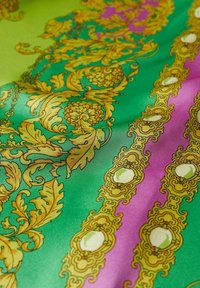 Groene en paarse stof met ingewikkelde gouden bloem- en ornamentale barokpatronen, met bladeren- en medaillonmotieven.