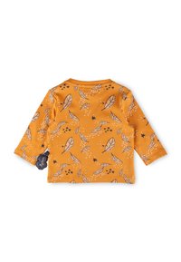 Langärmliges Baumwollshirt in Senfgelb mit einem Blatt- und Sternmuster in Dunkelblau und Weiß, mit rundem Ausschnitt und einem Etikett an der Seite.