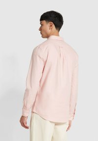 Camicia a maniche lunghe rosa chiaro in cotone, con colletto a punta e piega singola sul retro, e polsini con bottoni. Tessuto liscio, design aderente.