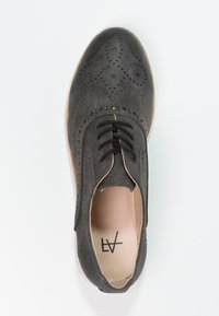 Chaussure en cuir noir avec des détails de brogue, design à lacets, semelle marron, bout arrondi et doublure intérieure lisse.