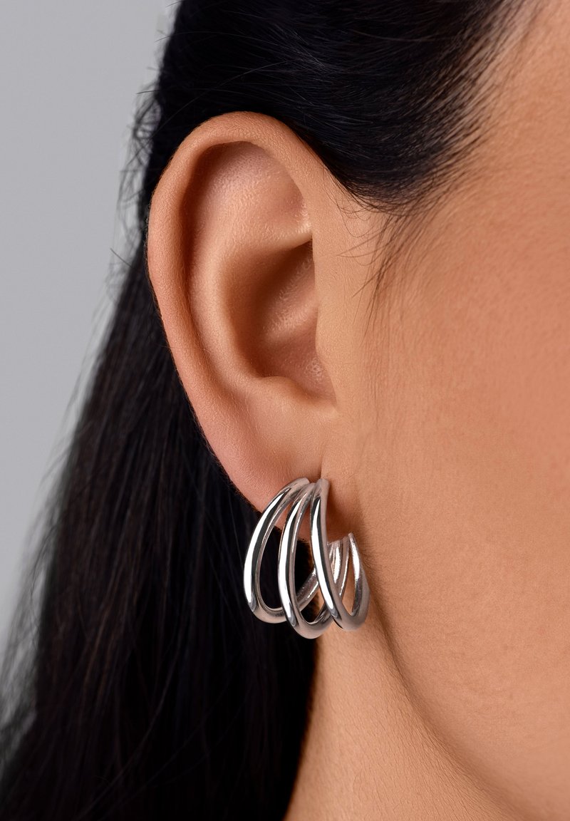 Boucles d'oreilles en argent avec quatre boucles entrelacées, mettant en valeur une finition métallique brillante et une texture lisse.