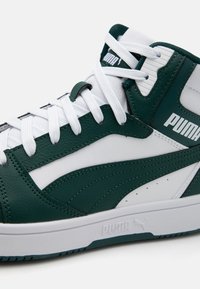 Zapatilla alta verde y blanca hecha de cuero, con cordones blancos planos, textura suave y el logo de Puma en el costado y en la lengüeta.