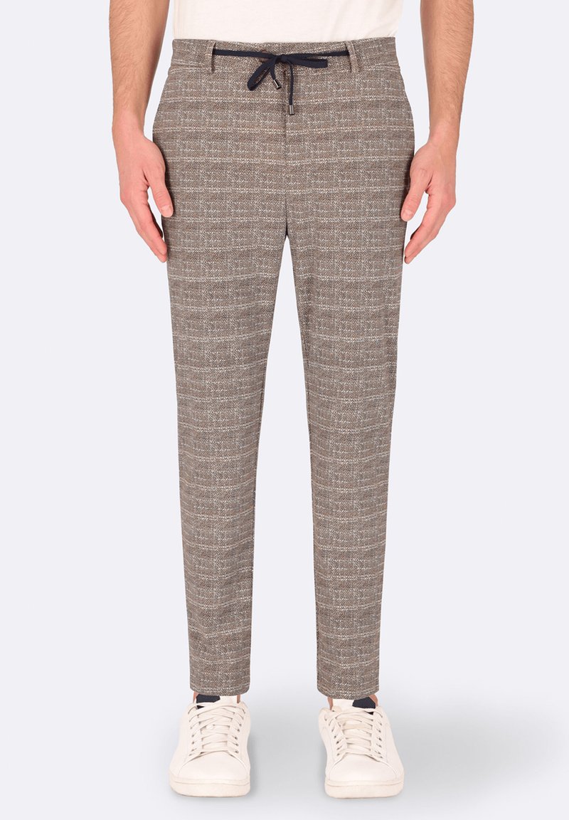 Pantaloni marroni a fantasia con vita regolabile, slim fit, tessuto testurizzato e delicato design a quadri. Abbinati a sneakers bianche.