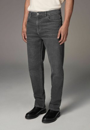Jeans din denim gri, cu o croială dreaptă, dotate cu buzunare frontale și o închidere cu un singur buton. Purtați cu cizme negre de tip slip-on.