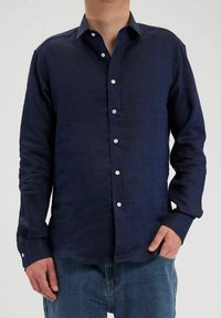 Chemise en lin bleu marine à manches longues, avec un bouton sur le devant et des boutons blancs. Dotée d'un col classique et d'une coupe décontractée.
