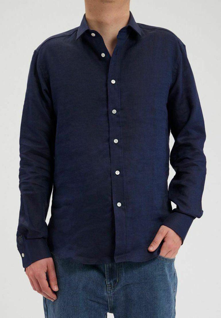 Chemise en lin bleu marine à manches longues, avec un bouton sur le devant et des boutons blancs. Dotée d'un col classique et d'une coupe décontractée.