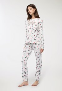 Set di pigiama bianco con motivo di pinguini e cuori rossi. Maglia a maniche lunghe con collo rotondo, abbinata a pantaloni aderenti. Tessuto morbido.