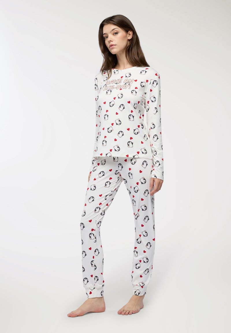 Set di pigiama bianco con motivo di pinguini e cuori rossi. Maglia a maniche lunghe con collo rotondo, abbinata a pantaloni aderenti. Tessuto morbido.
