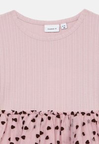 Abito per bambina di colore rosa con righe, dotato di una gonna in rete con motivi a cuori neri, scollatura rotonda e piccolo etichetta bianca del marchio all'interno del colletto.