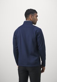 Giacca in pile blu navy con colletto alto, tessuto testurizzato e maniche lunghe, caratterizzata da un sottile motivo tonale.