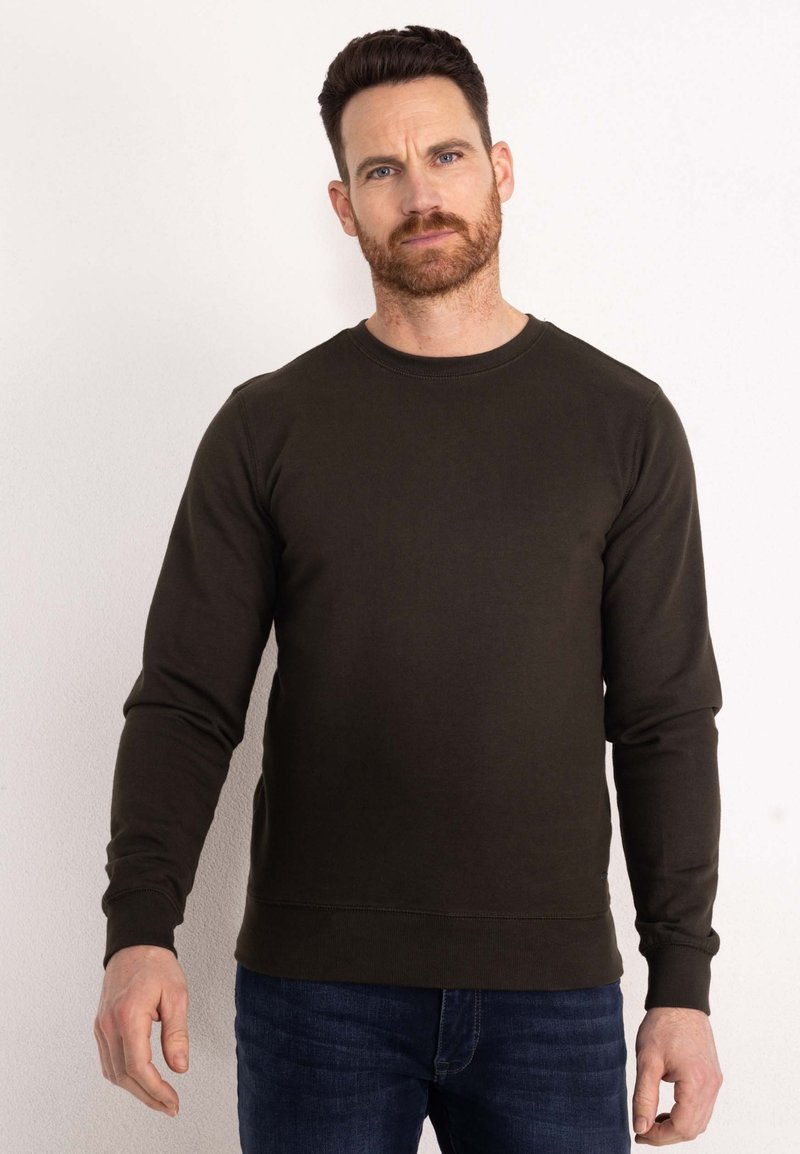 Dark green sweatshirt with long sleeves, round neck, ribbed cuffs, and hem. Smooth texture, minimal stitching details, worn with blue jeans.