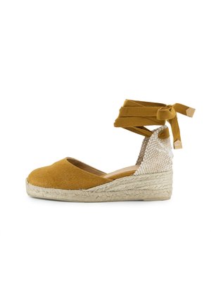 Espadrilla giallo senape con tomaia in tessuto, suola intermedia in juta intrecciata e retro testurizzato. Presenta lacci alla caviglia per una vestibilità regolabile.