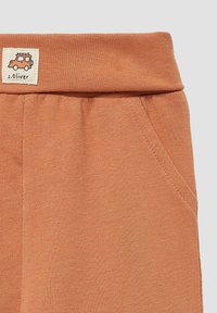 Joggingbroeken van een katoenmix in een roest-oranje kleur, met een elastische tailleband en zijzakken; een klein geborduurd voertuillogo op de tailleband.