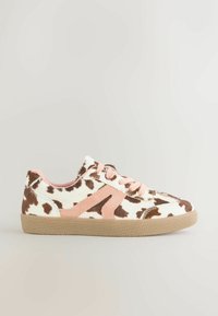 Weißer Sneaker mit braunem Kuhmuster und rosa Wildledereinsätzen. Runde Zehenpartie, Schnürverschluss und strukturiertes Gummisohle.