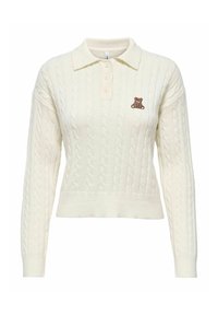 Pulover od pletiva u krem boji s ovratnikom i tri dugmeta. Ima malu vezenu smeđu plišanu medvjedicu na prsima.