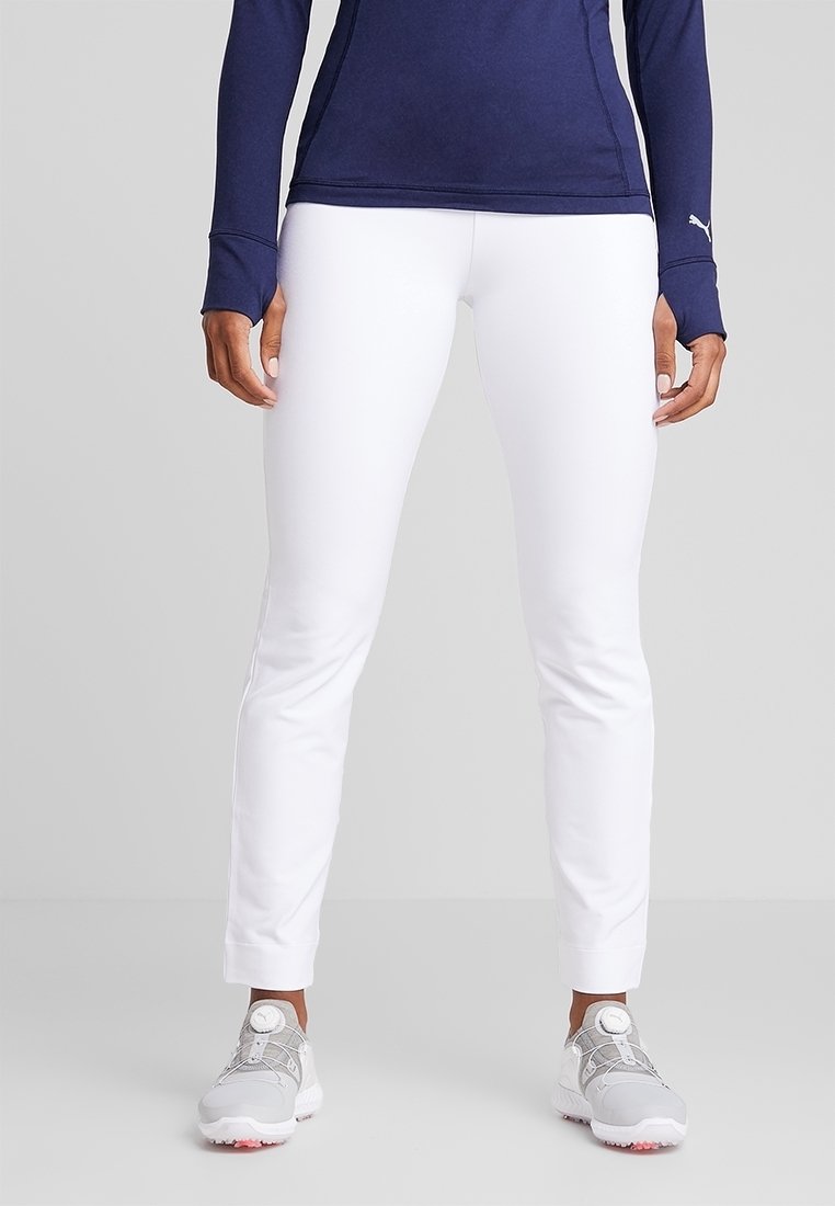 Vita träningsbyxor med slim fit, tillverkade av ett slätt material. Kombineras med grå sneakers med ett unikt snörningssystem.